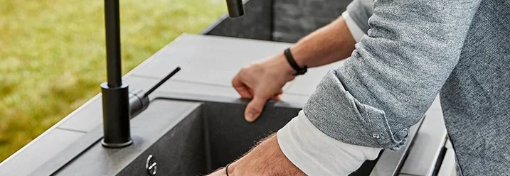 Person hebt Spüle in Außenküche ein